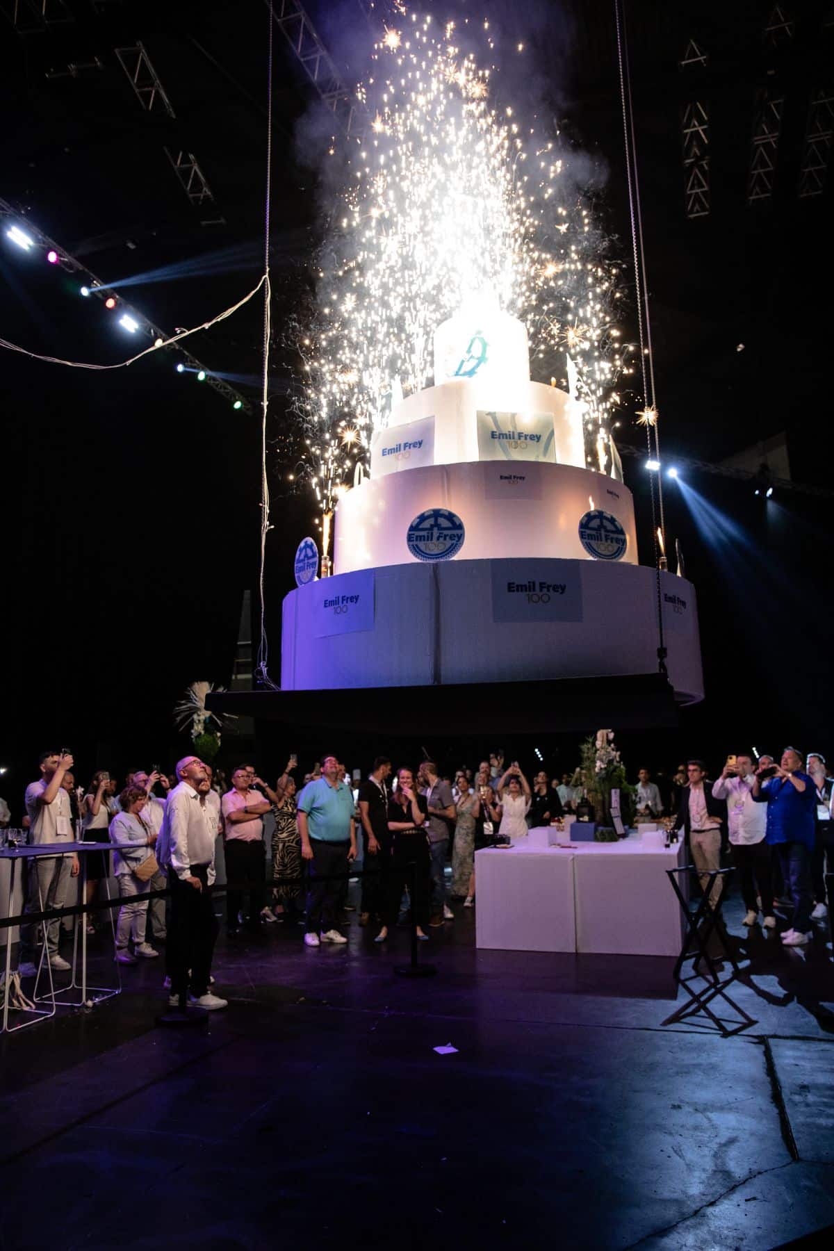 Eclairé par des feux de bengale; le gâteau anniversaire des 100 ans du groupe Emil Frey descend sur une nacelle.